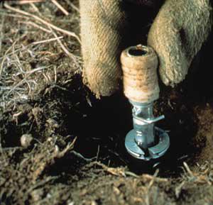 A hand touching a device set in the ground