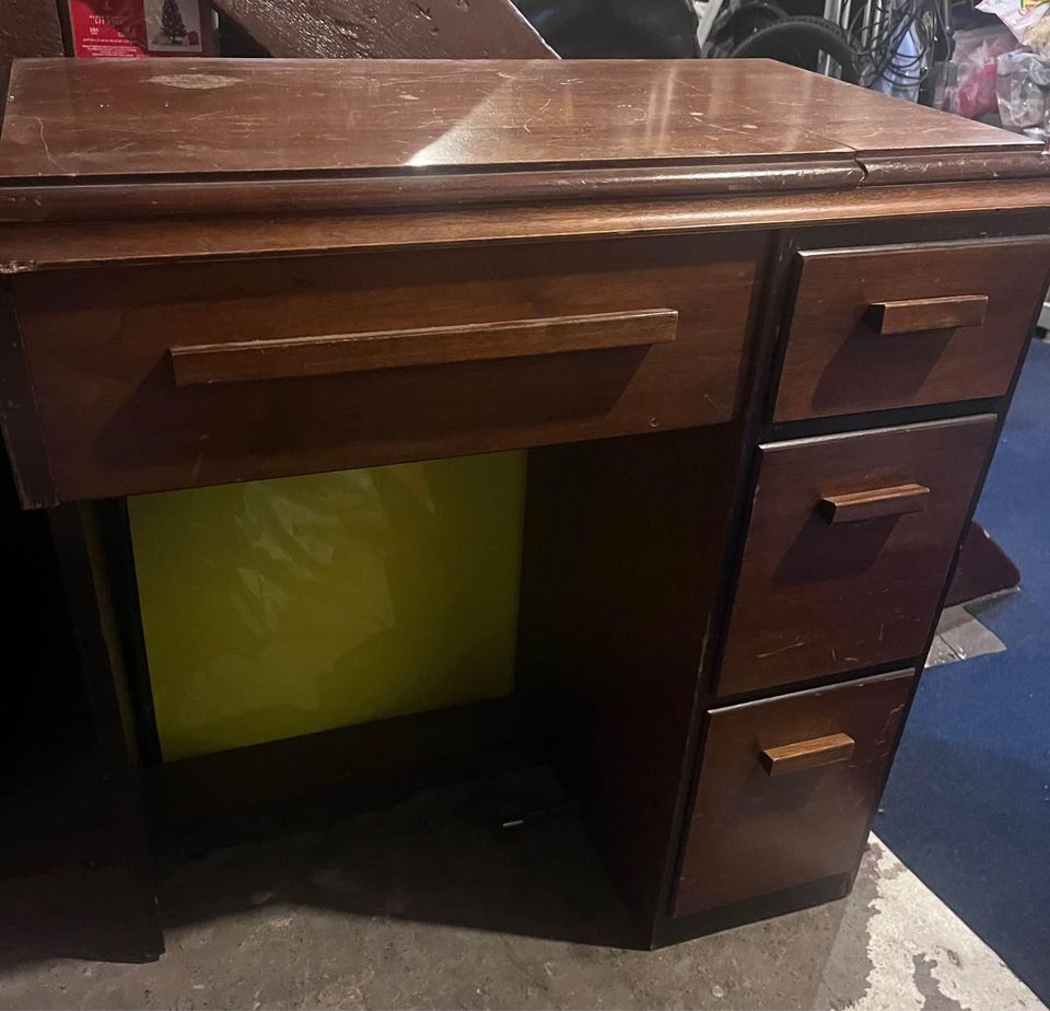 A vintage sewing machine cabinet in dark wood
