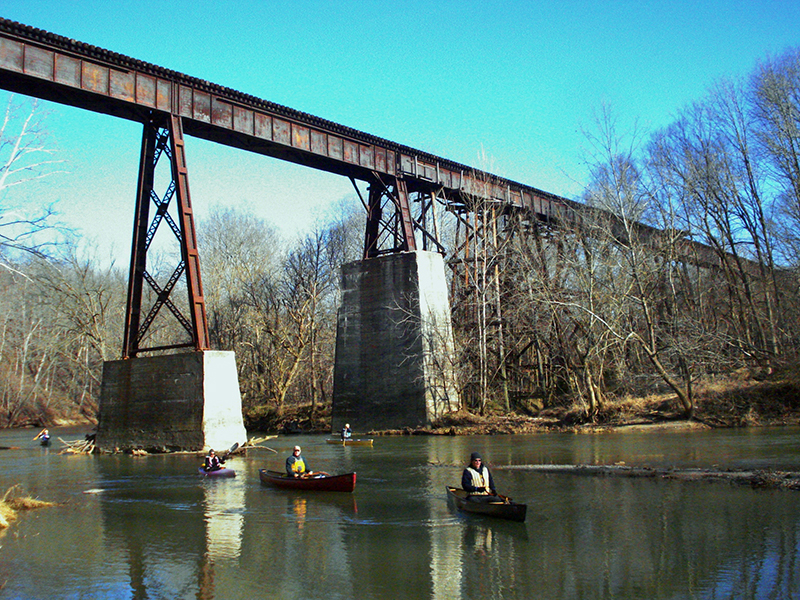A high railroad trestle bridge. It is decaying and rusty.